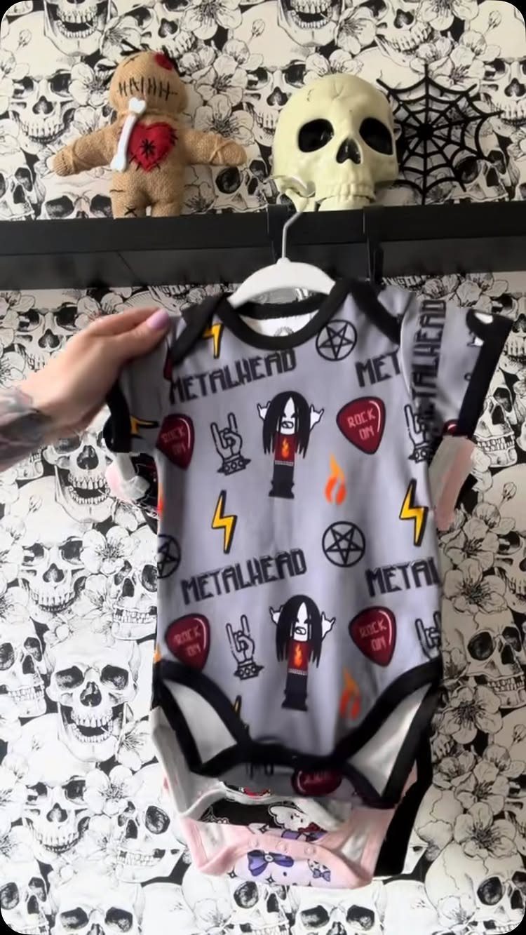 Rockstar Infant Clothing Ideas: 5 Looks for Little Rockers 2 Grey infant bodysuit with metalhead graphics hanging against skull patterned wallpaper