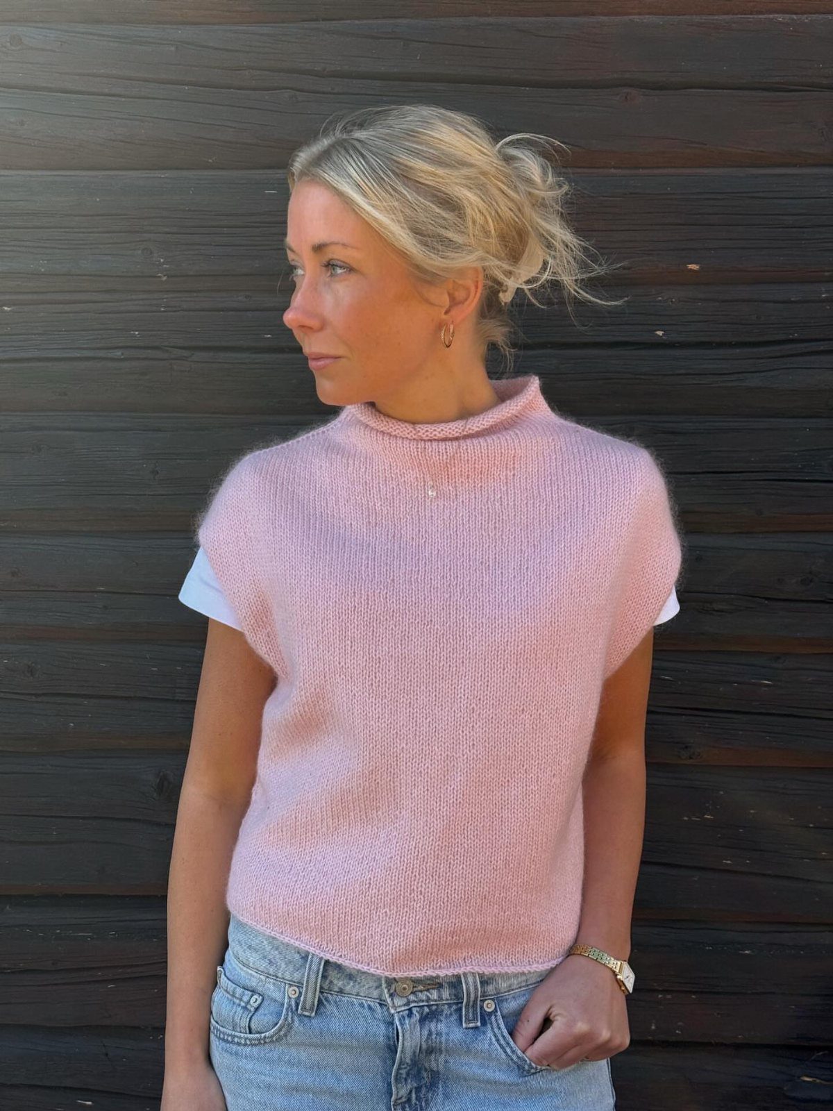 Swedish Women's Clothing Ideas: 8 Outfits to Wear Now 5 Woman wearing a pink knitted sleeveless turtleneck and light blue denim jeans.