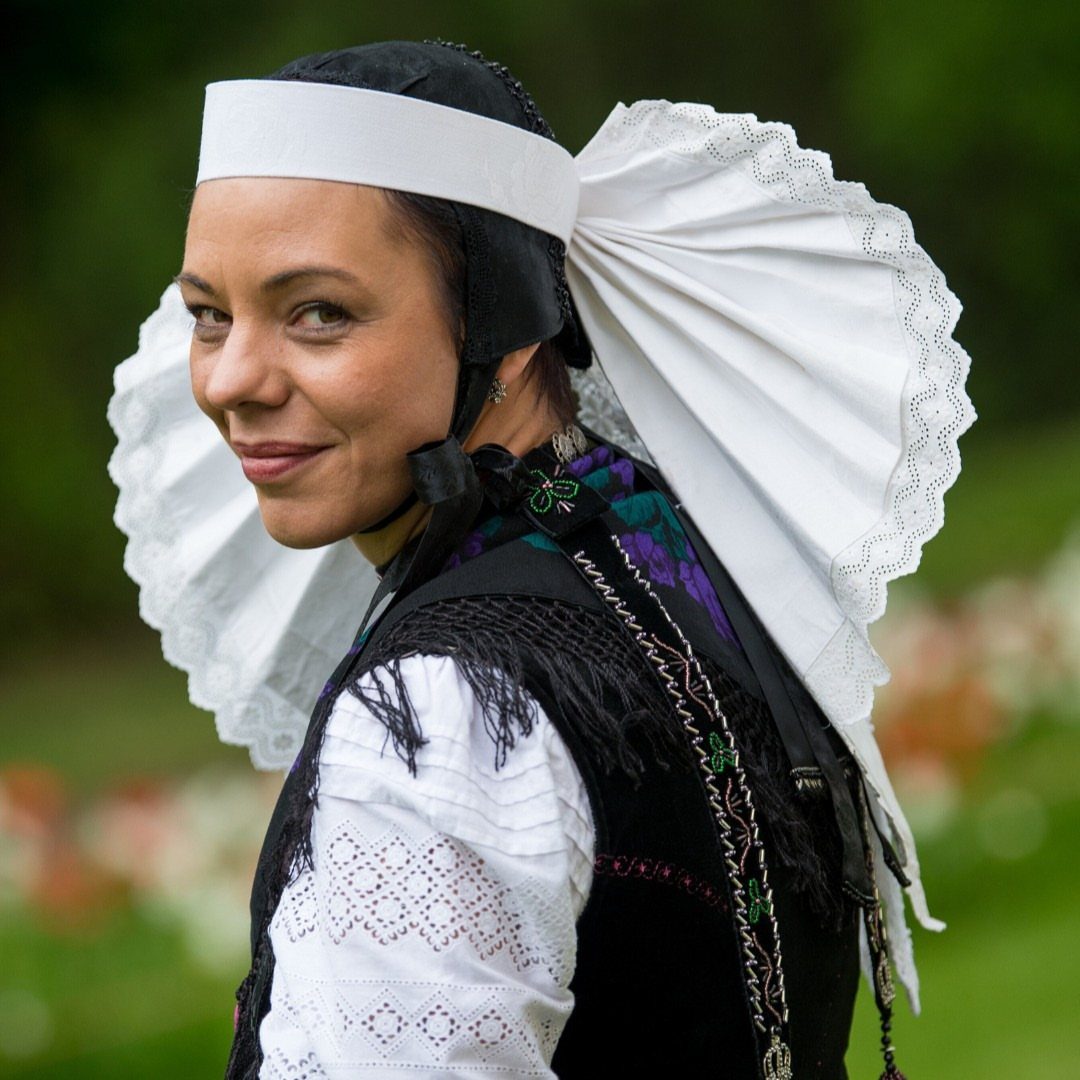 Woman wearing a traditional costume with a large white pleated lace headdress.